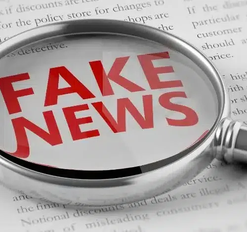 Imagem com uma lupa enfatizando a palavra Fake News em vermelho.